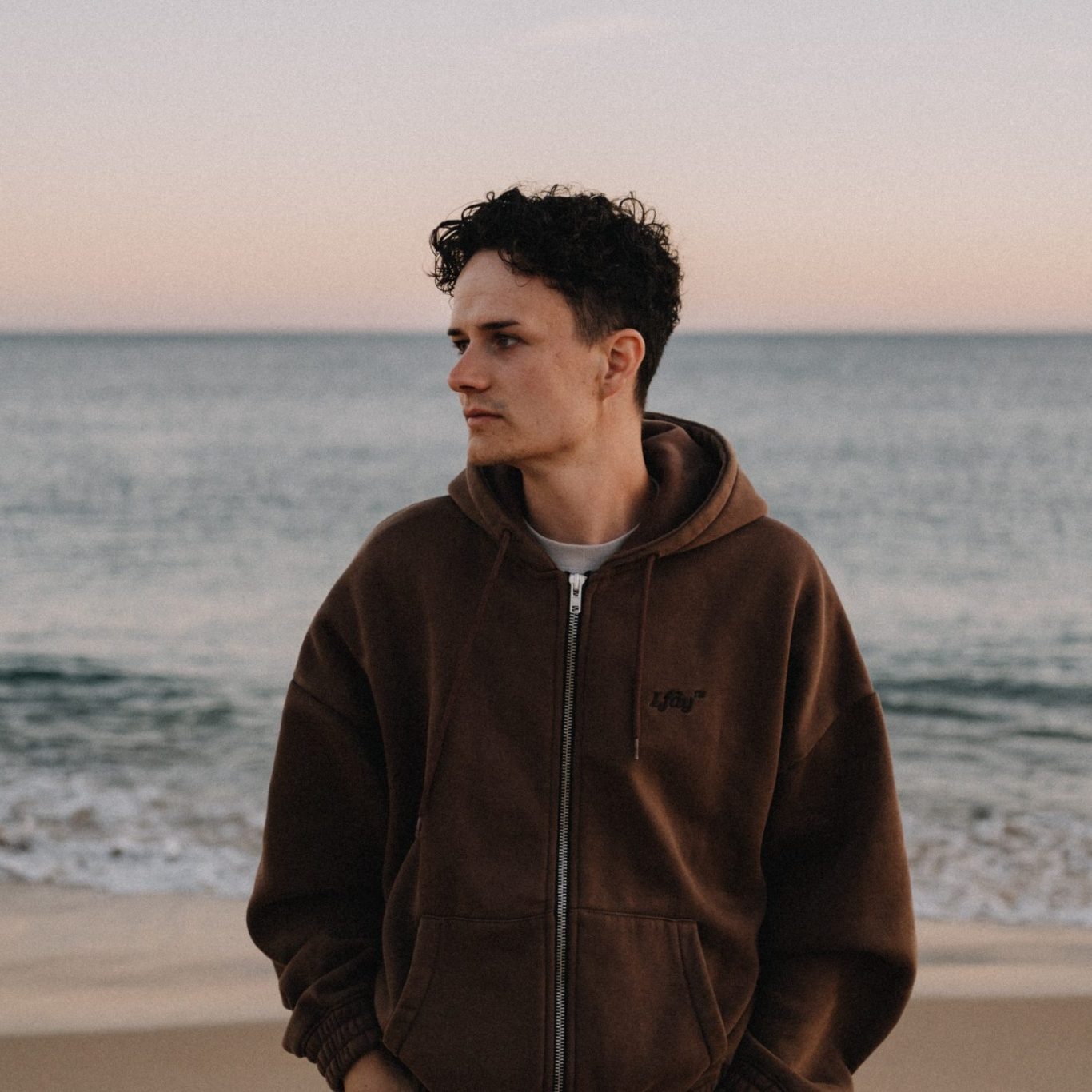Portrait von Tobias Heimann am Strand vor dem Meer bei Sonnenuntergang